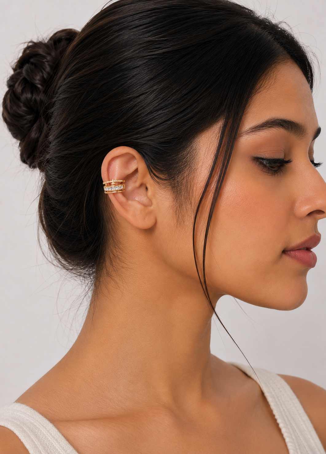 Gold tone ear cuff with crystal baguette stones worn on the middle ear cartilage without piercing.