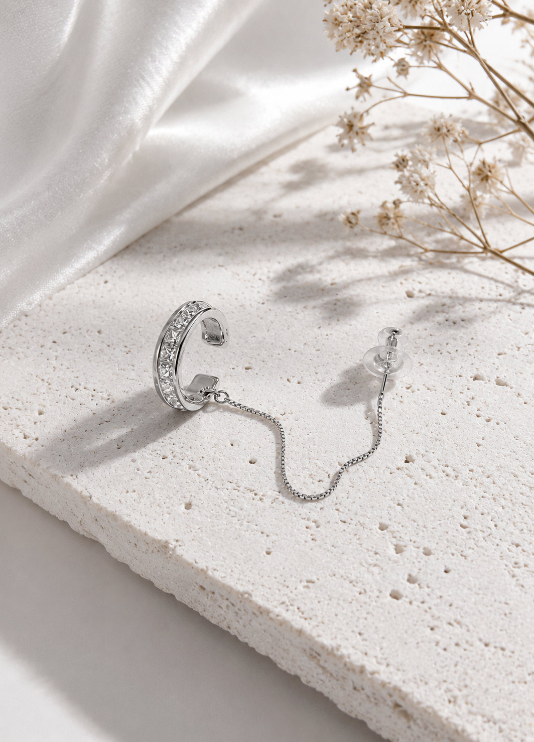 Orelva silver chain ear cuff stud earrings displayed on a premium stone surface.