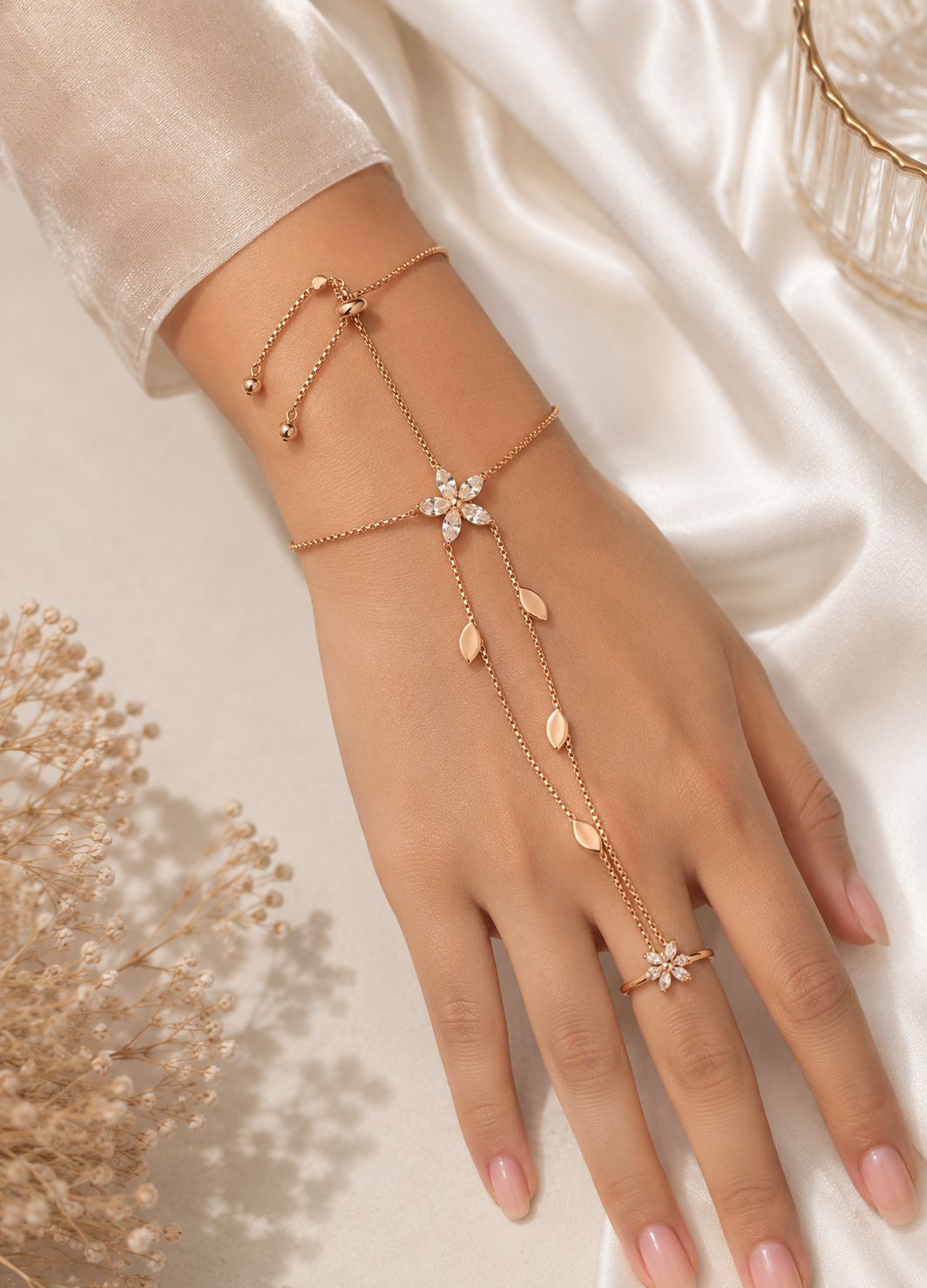 Woman wearing Orelva rose gold floral hand harness bracelet with crystal flower and matching finger ring.