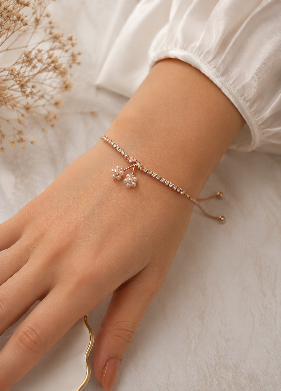 Orelva rose gold pearl blossom adjustable bracelet worn on a woman's wrist