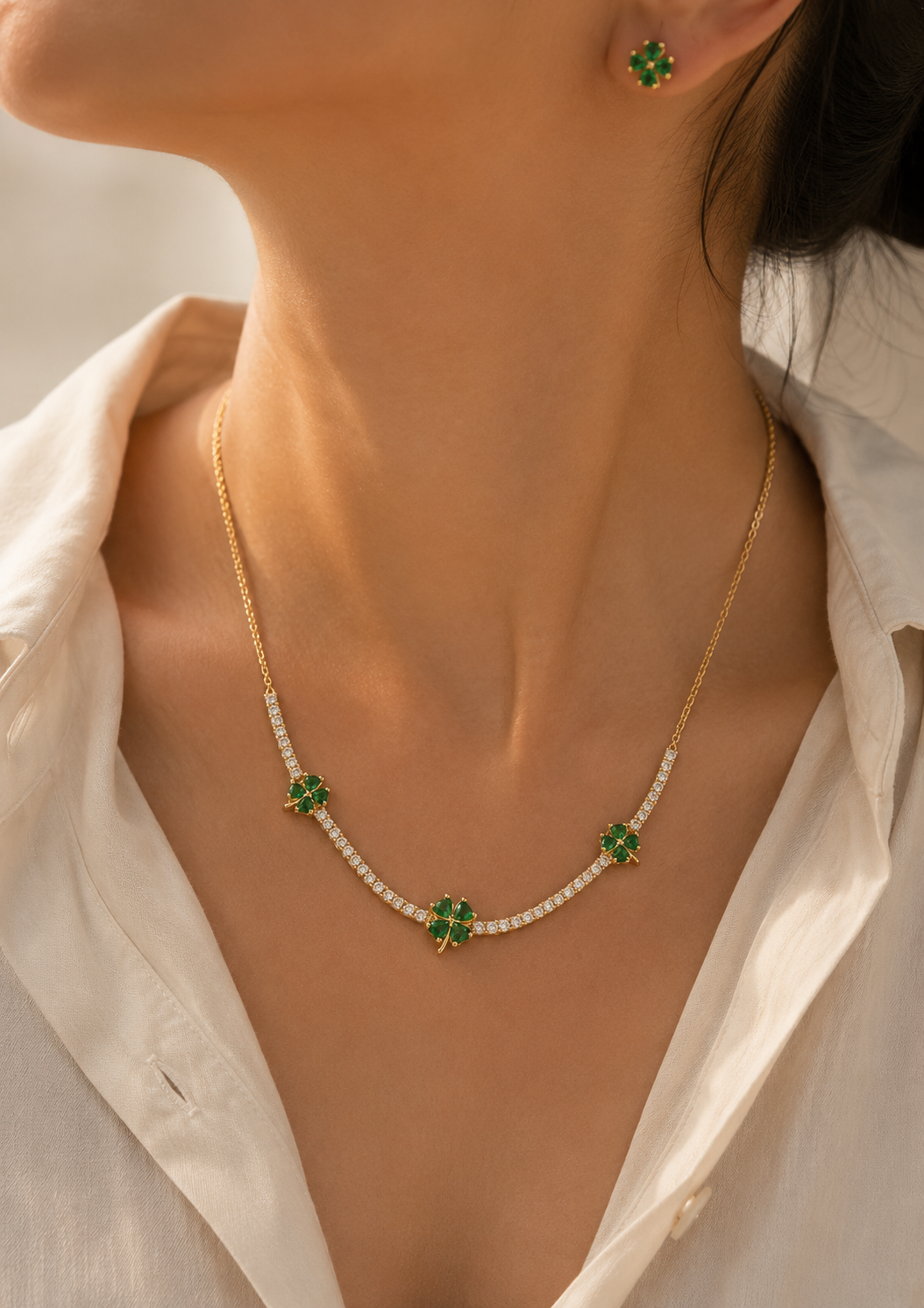 Elegant gold-tone necklace and earrings featuring green clover crystals and white stone accents.