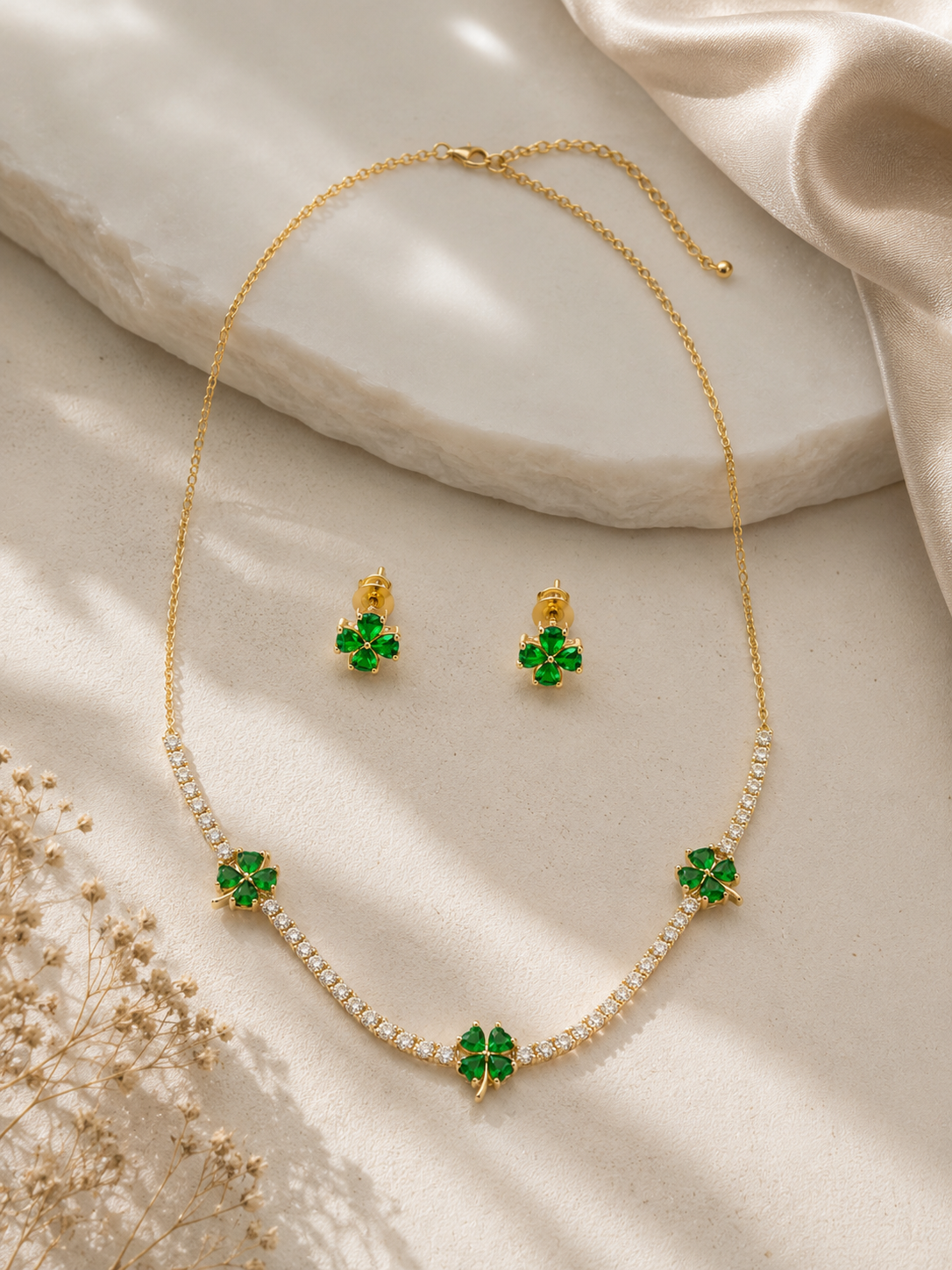 Women's gold-tone clover necklace and stud earrings set with emerald green crystal flower design.