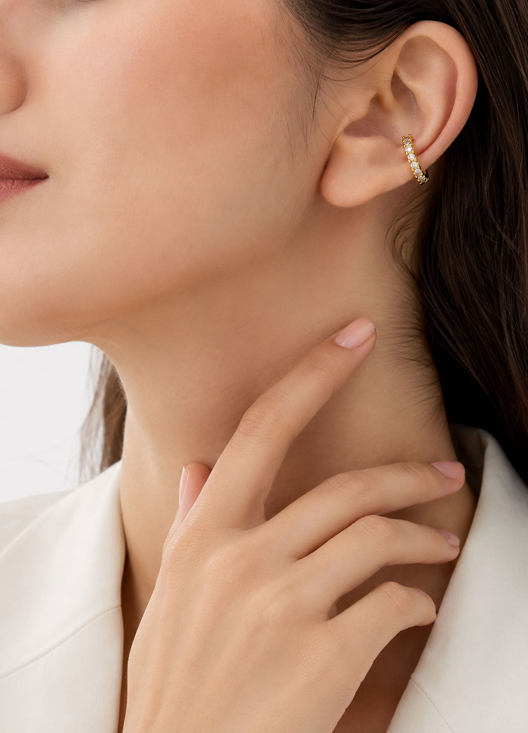 Woman wearing Orelva Aurora gold crystal ear cuff with sparkling cubic zirconia stones.
