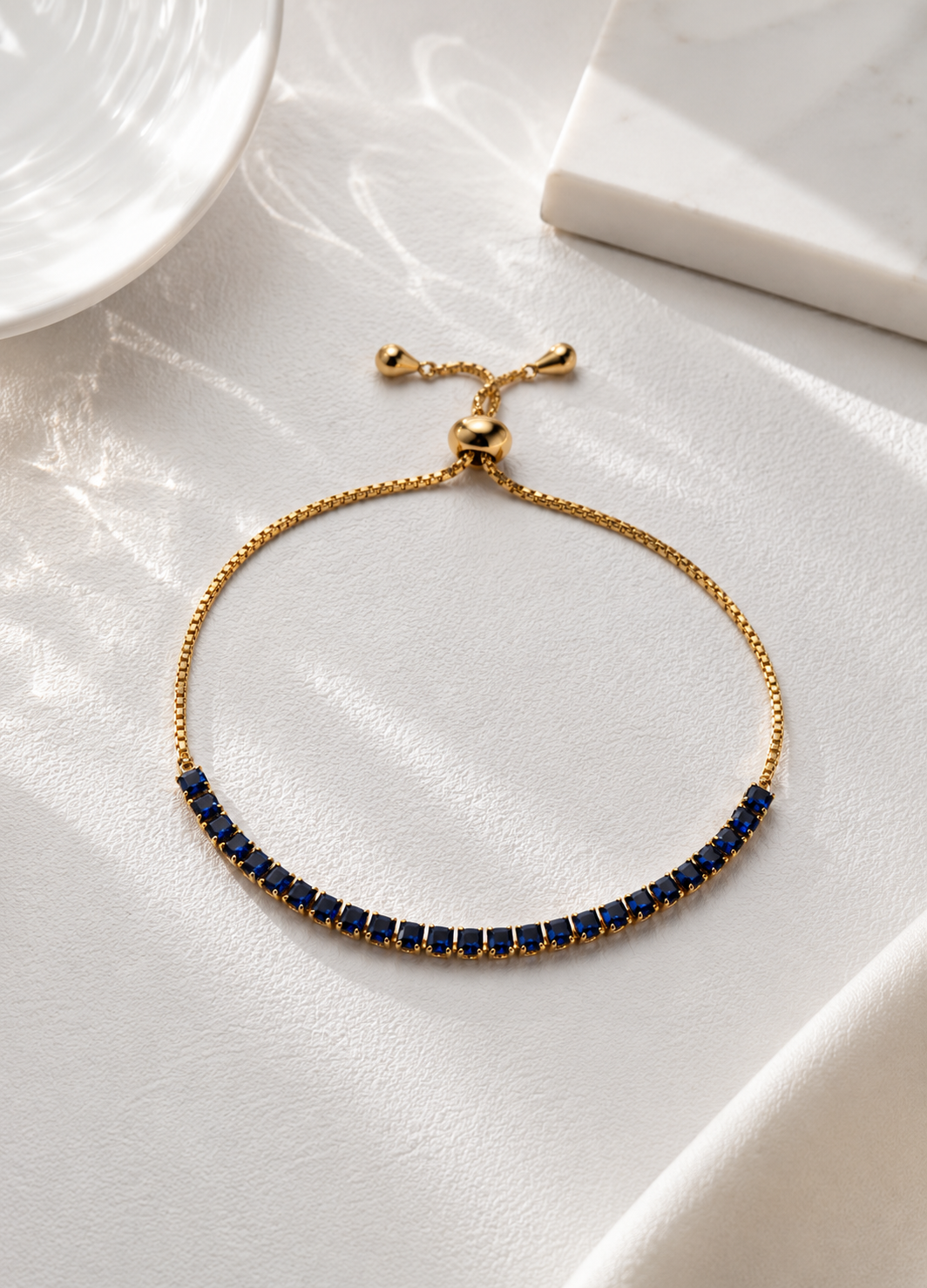 ORELVA Azure Line gold-plated adjustable tennis bracelet featuring deep blue crystal stones.