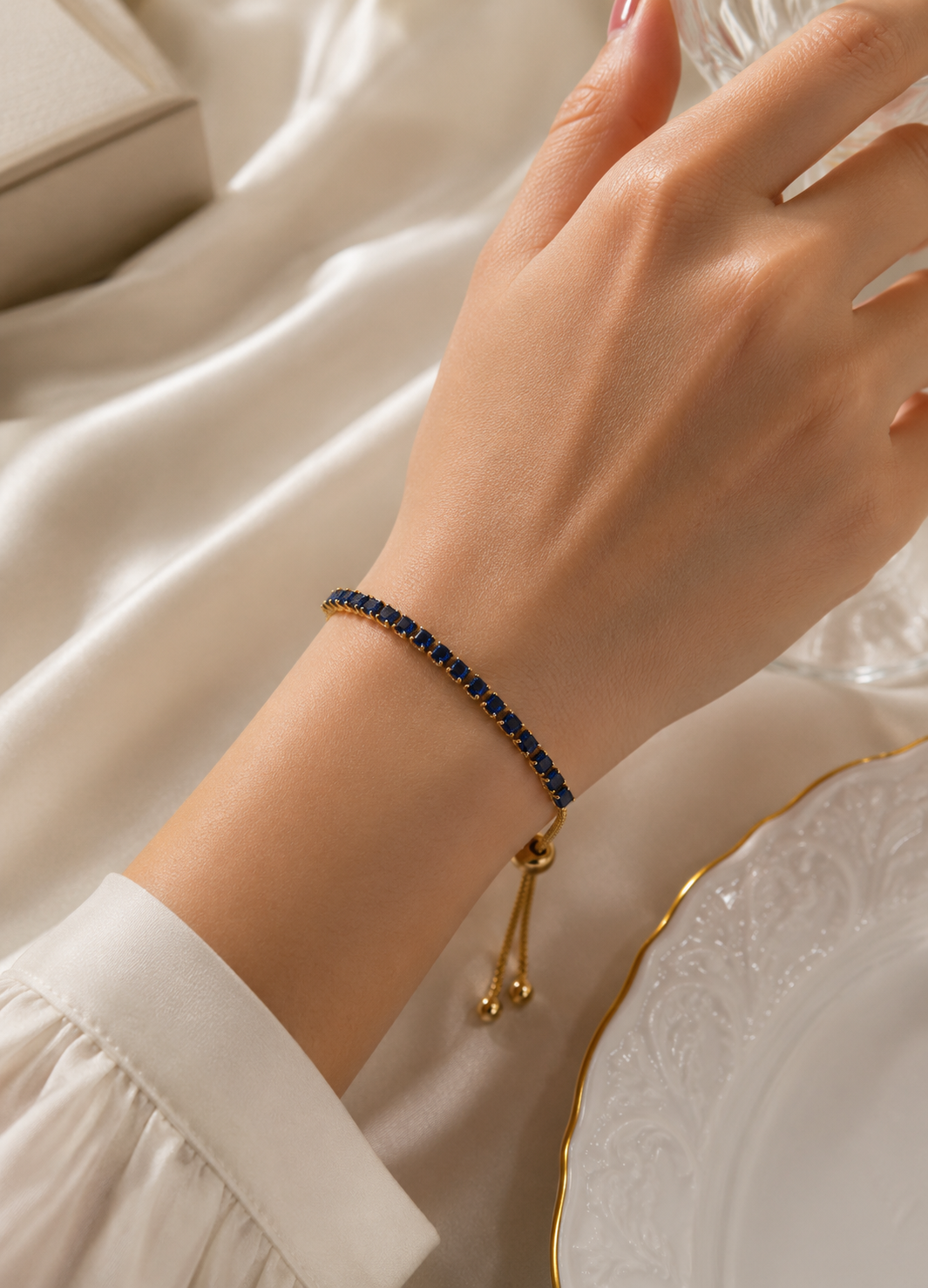 Woman wearing ORELVA Azure Line adjustable gold-plated bracelet with blue crystal stones.