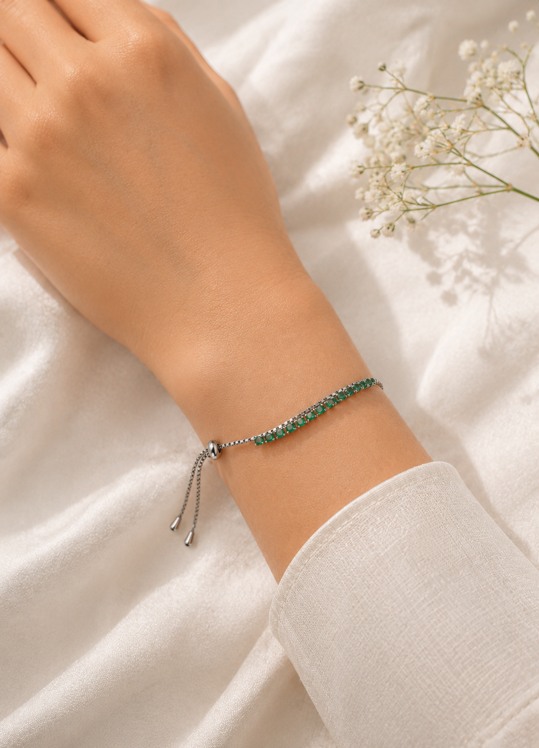 Woman wearing ORELVA Emerald Glow adjustable silver bracelet with green crystal stones.