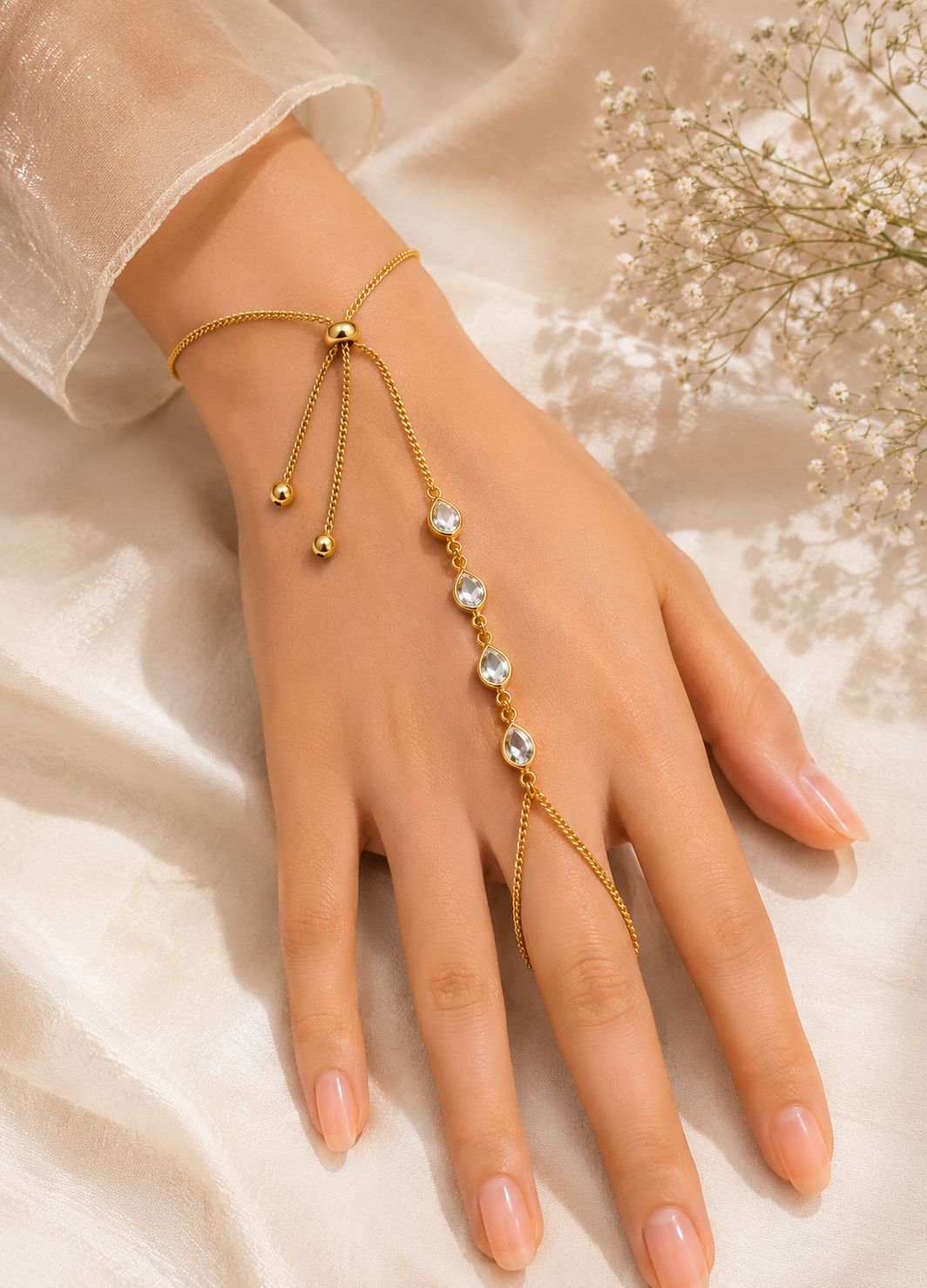 Woman wearing Orelva gold adjustable hand harness bracelet with sparkling teardrop crystal accents.