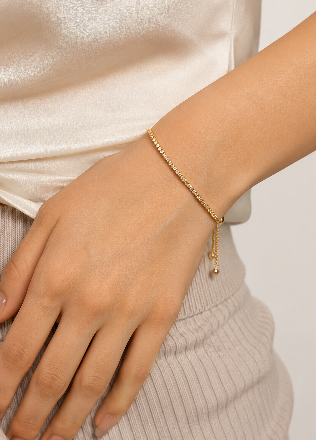Orelva gold crystal tennis bracelet worn on a woman's wrist