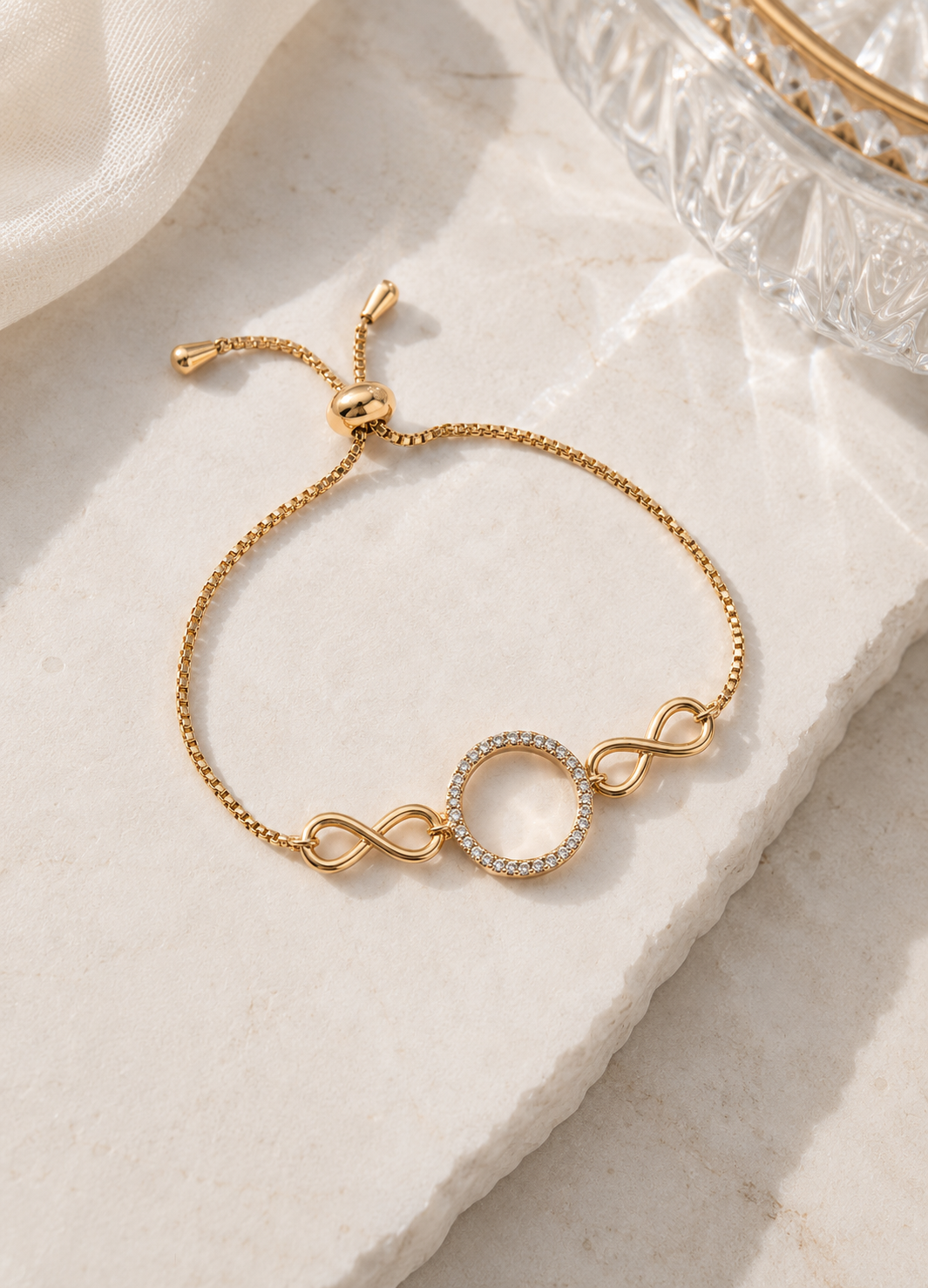 ORELVA Gold-Plated Infinity Halo Adjustable Bracelet with crystal-studded circular centerpiece.