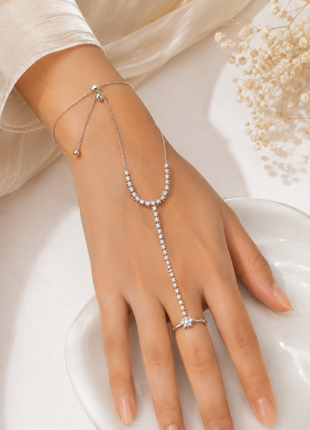 Orelva silver crystal hand harness bracelet ring worn on a woman's hand with an elegant floral design.