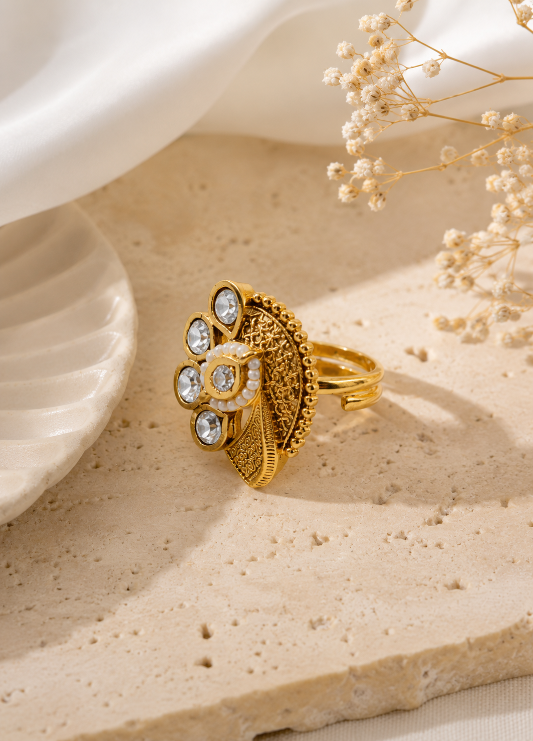 ORELVA Varnika floral adjustable Kundan ring displayed on a premium beige stone surface with elegant styling.