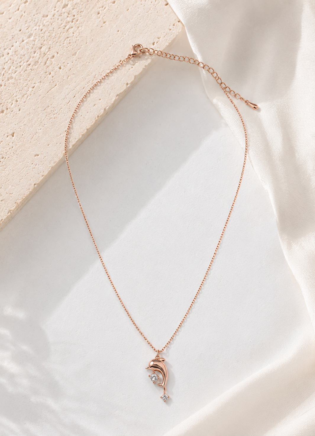 Close-up of ORELVA rose gold dolphin pendant necklace featuring brilliant cubic zirconia stones
