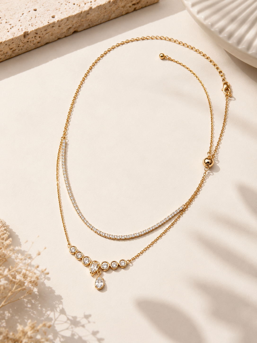 Elegant rose gold tone layered necklace featuring crystal strand and drop pendant