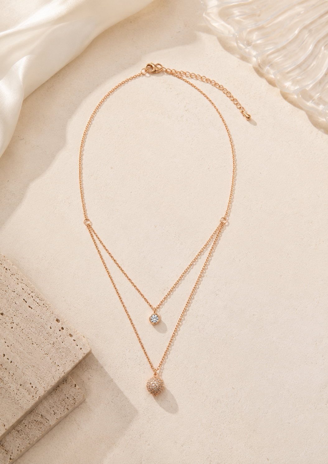 Elegant rose gold tone layered necklace featuring a pavé crystal disc pendant
