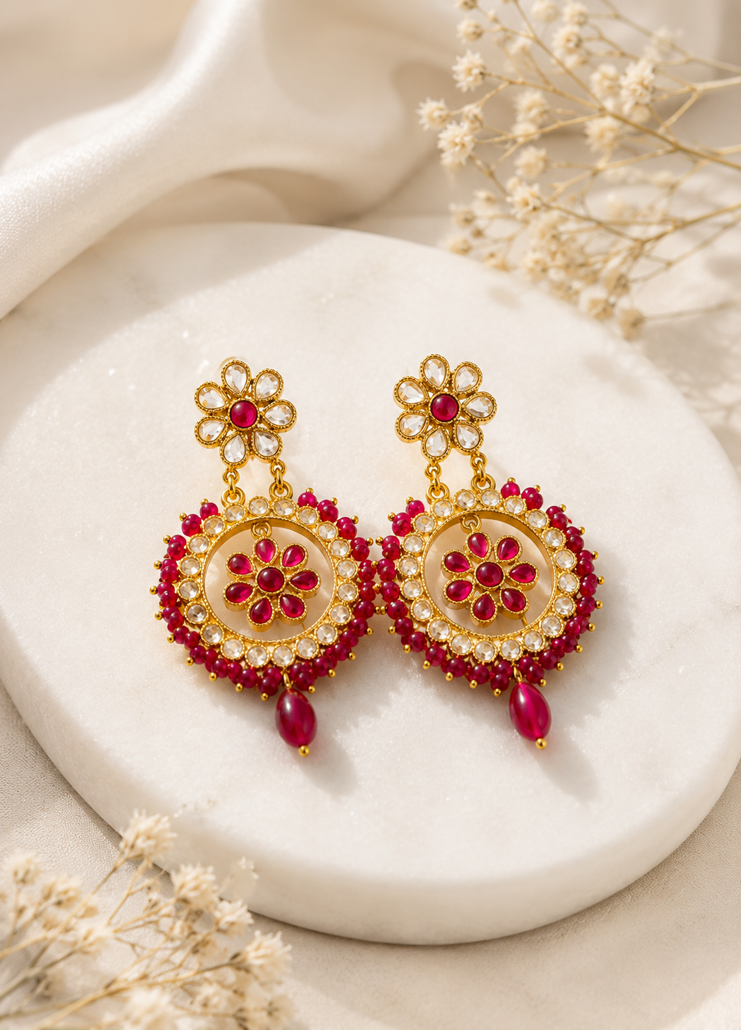 Premium ruby floral Kundan Chandbali earrings displayed on a marble surface with elegant styling.